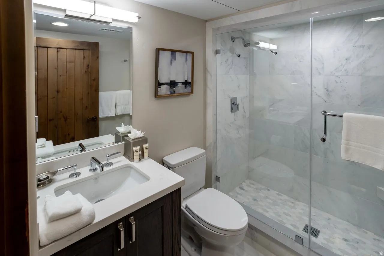 Contemporary bathroom featuring a glass-enclosed shower with full-height tile, a single vanity with an undermount sink, and a dark wood-finish vanity cabinet