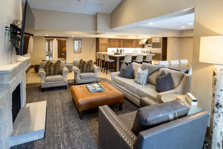 Open-concept living area featuring a stone fireplace, wood-finish flooring, recessed lighting, and a kitchen with an island and integrated appliances