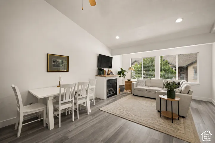 Open-concept living area with vaulted ceilings, gray wood-finish flooring, and recessed lighting