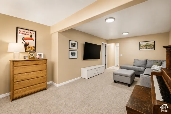 Carpeted room featuring a recessed ceiling beam and neutral wall tones