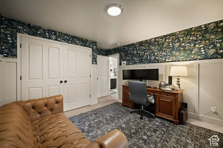 Interior room featuring white board and batten wainscoting with botanical wallpaper, ceiling-mounted lighting, and paneled doors