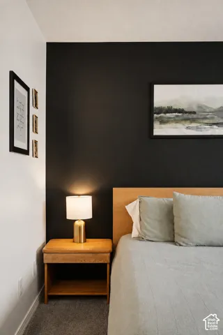 Accent wall with contrasting paint, wood-finish flooring, and a light wood headboard