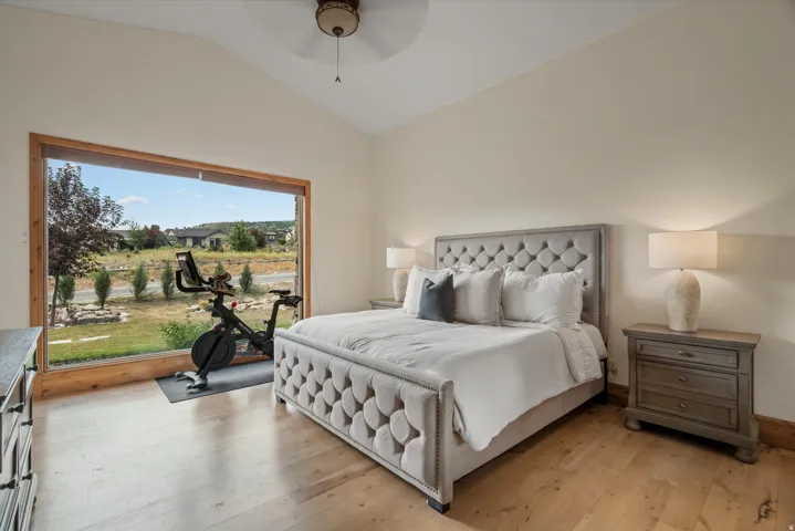 Vast picture window, vaulted ceiling, wood-finish flooring, recessed lighting, and a ceiling fan