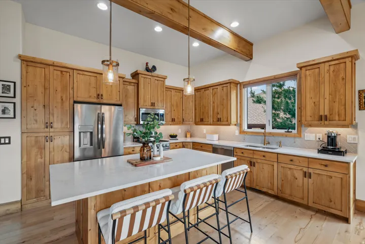 Spacious kitchen featuring extensive wood cabinetry, a large center island with a white countertop, and stainless steel appliances