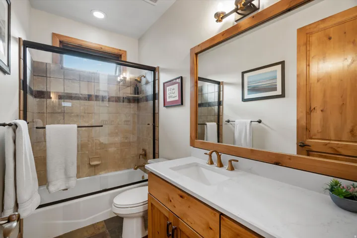 Bathroom featuring a natural wood vanity with a white countertop and undermount sink, bronze-finish faucet, and a large wood-framed mirror