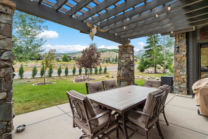 Expansive covered patio featuring a wood pergola and stone columns