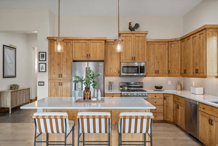 Kitchen featuring natural wood cabinetry, stainless steel appliances, and a central island with a light-toned countertop