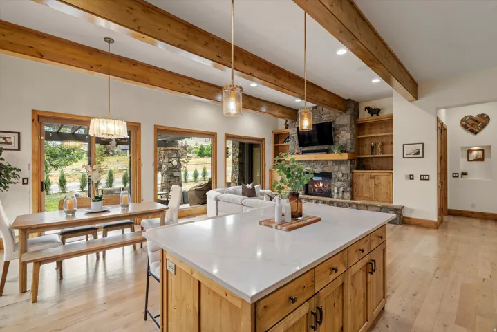 Spacious open-concept interior featuring light wood-finish flooring and exposed ceiling beams