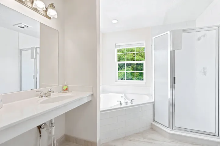 Bathroom featuring a dual vanity with white countertop, chrome fixtures, and an overhead light bar