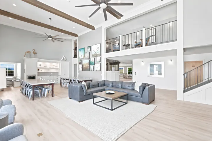 Expansive open-concept space featuring soaring ceilings with exposed wood beams and ceiling fans