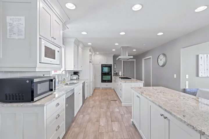 Spacious kitchen featuring white cabinetry, light-toned countertops, and wood-finish flooring