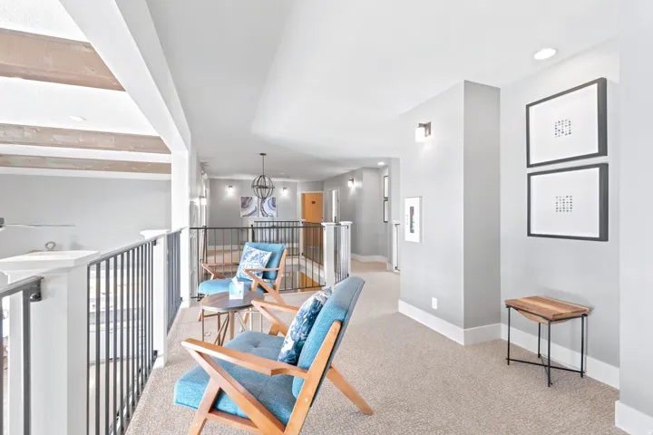 Upper-level hallway featuring neutral carpeting, white trim, and light gray walls with sconce lighting