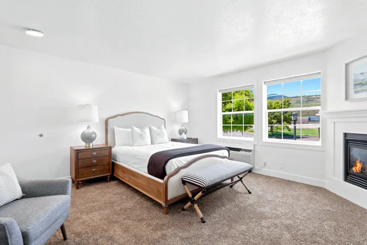 Carpeted room featuring a white fireplace, two large windows, and recessed lighting