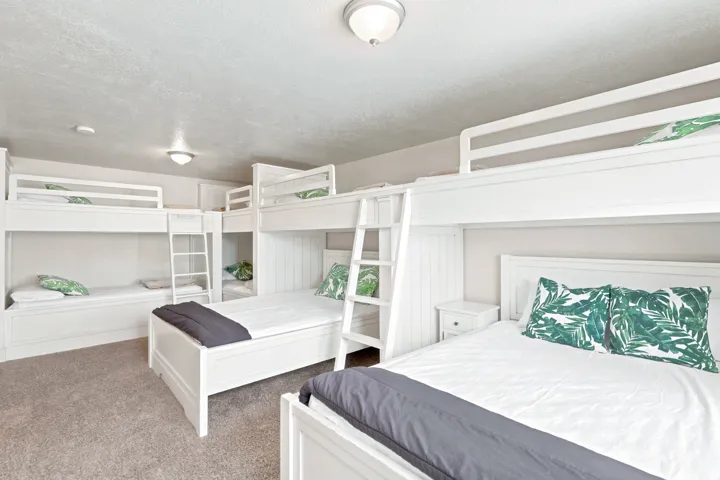 Spacious bedroom featuring multiple built-in white bunk beds, light gray wall paint, and recessed lighting