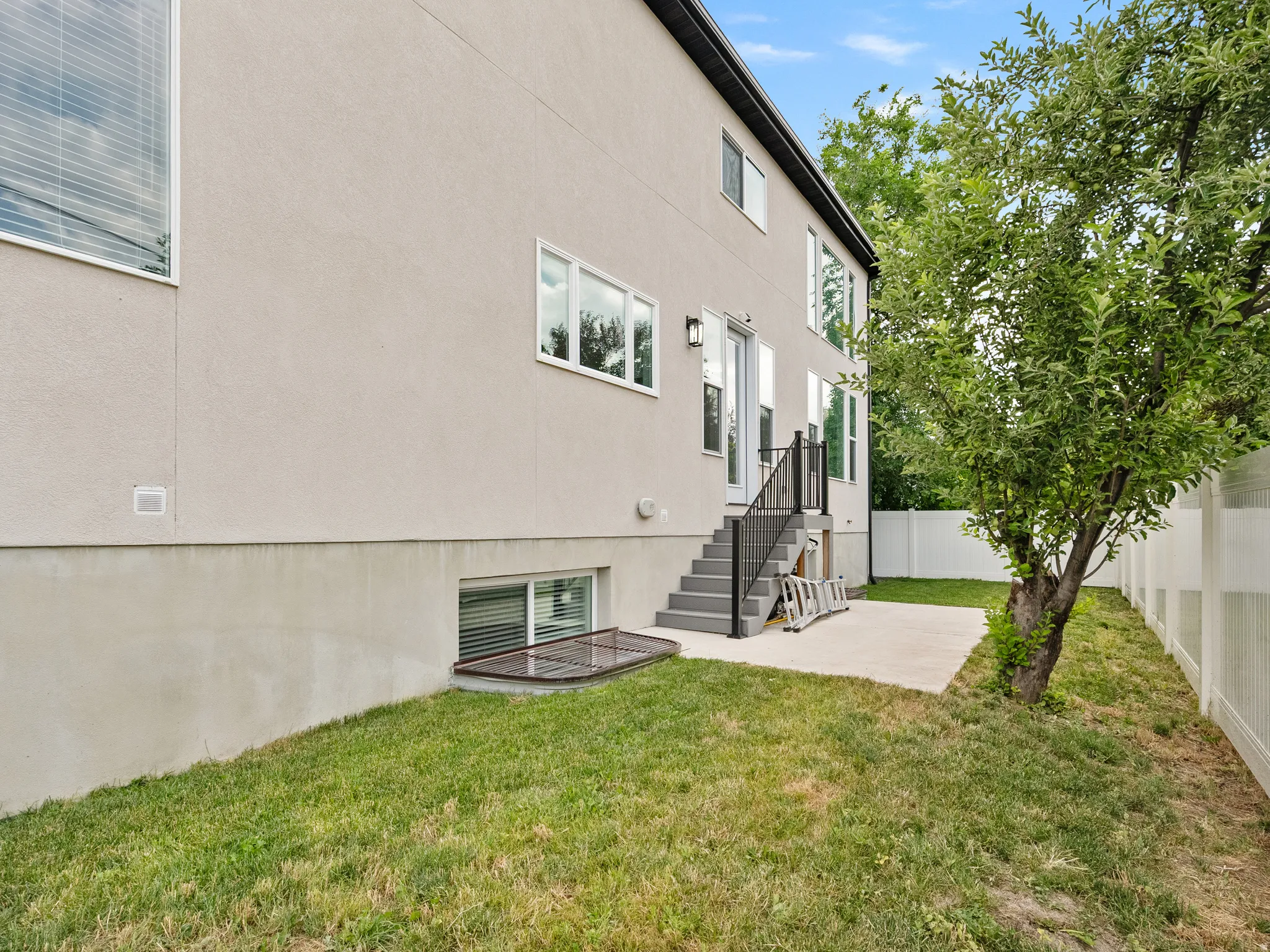 Rear exterior featuring a stucco finish, multiple windows, and a raised patio with steps