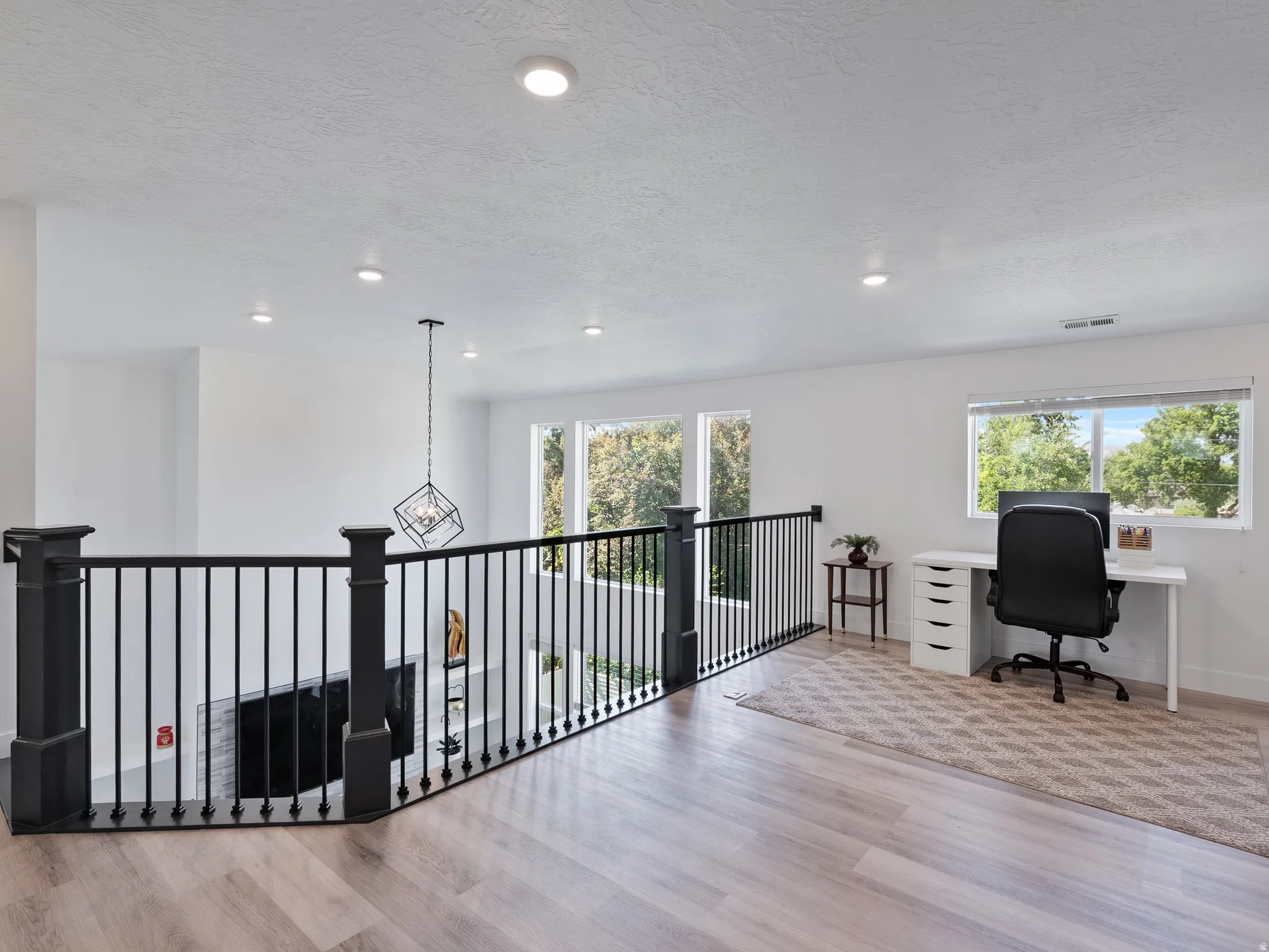 Upper-level landing featuring light wood-finish flooring, recessed lighting, and expansive windows