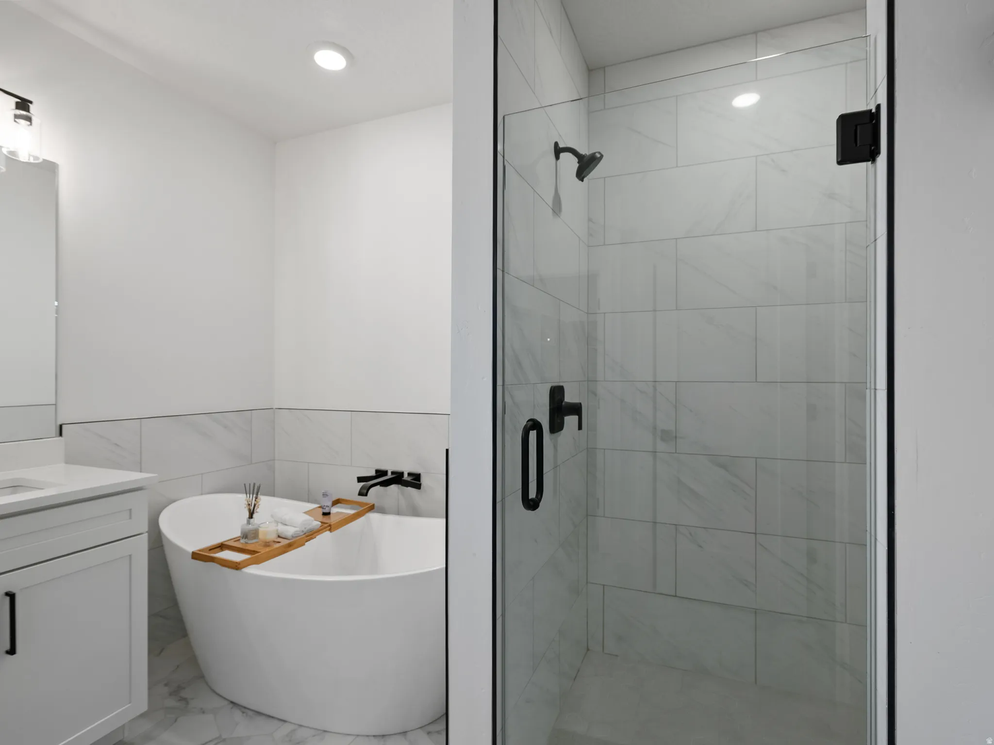 Freestanding soaking tub and glass-enclosed shower with contrasting matte black fixtures