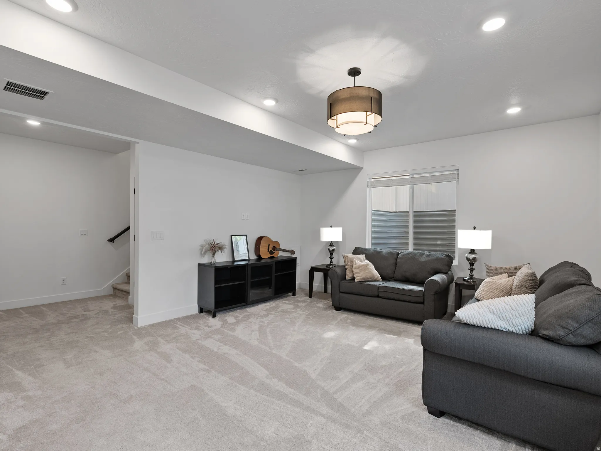 Spacious room featuring light-colored carpeting, recessed lighting, and a contemporary ceiling fixture
