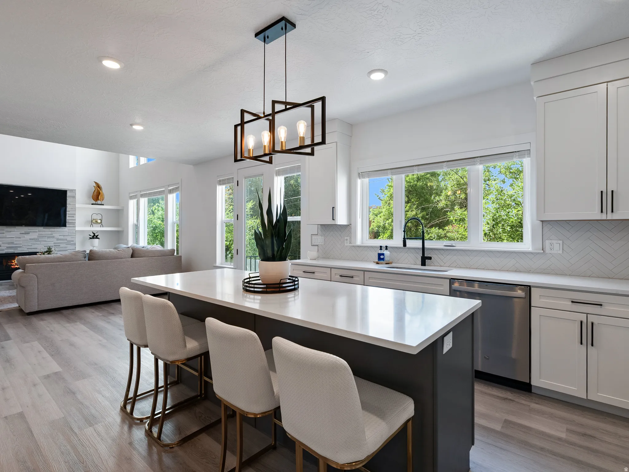 Modern kitchen featuring a large central island with seating, white shaker-style cabinetry, and a herringbone tile backsplash