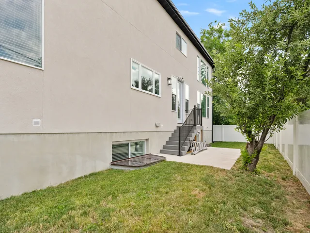 Rear exterior featuring a stucco finish, multiple windows, and a raised patio with steps