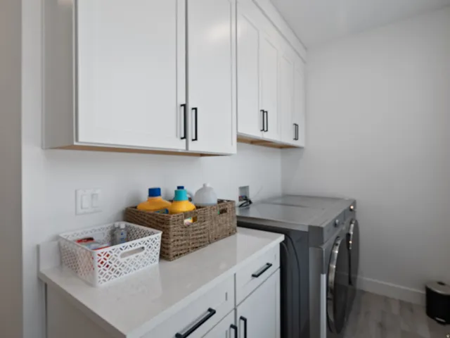 White shaker cabinetry with black hardware, white countertop, and wood-finish flooring