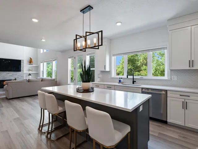 Modern kitchen featuring a large central island with seating, white shaker-style cabinetry, and a herringbone tile backsplash
