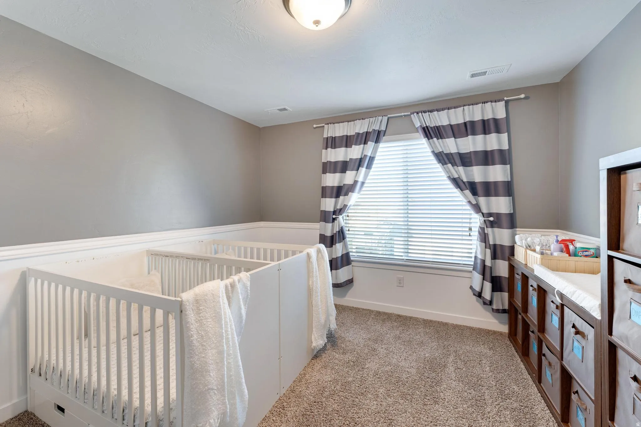 Room featuring a window with horizontal blinds, overhead flush mount lighting, and neutral wall paint