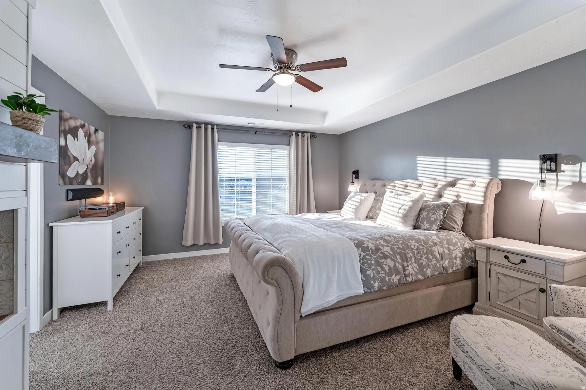 Spacious room featuring a tray ceiling, recessed window with blinds, ceiling fan, and carpeted flooring