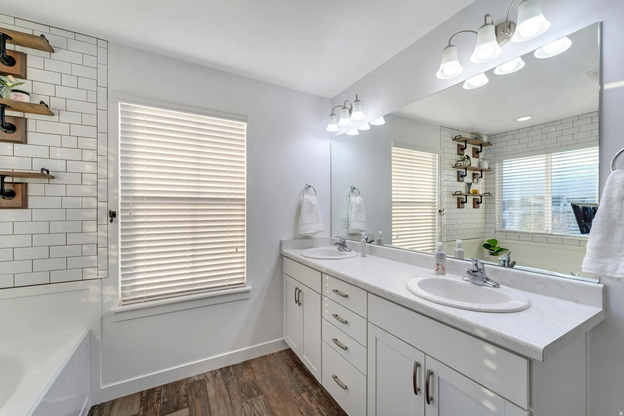 Dual vanity with white cabinetry and integrated sinks, complemented by a large wall-mounted mirror