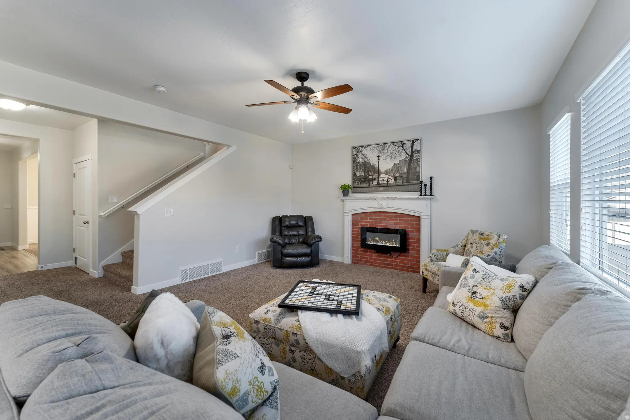 Living area with a modern electric fireplace featuring a brick surround and white mantel