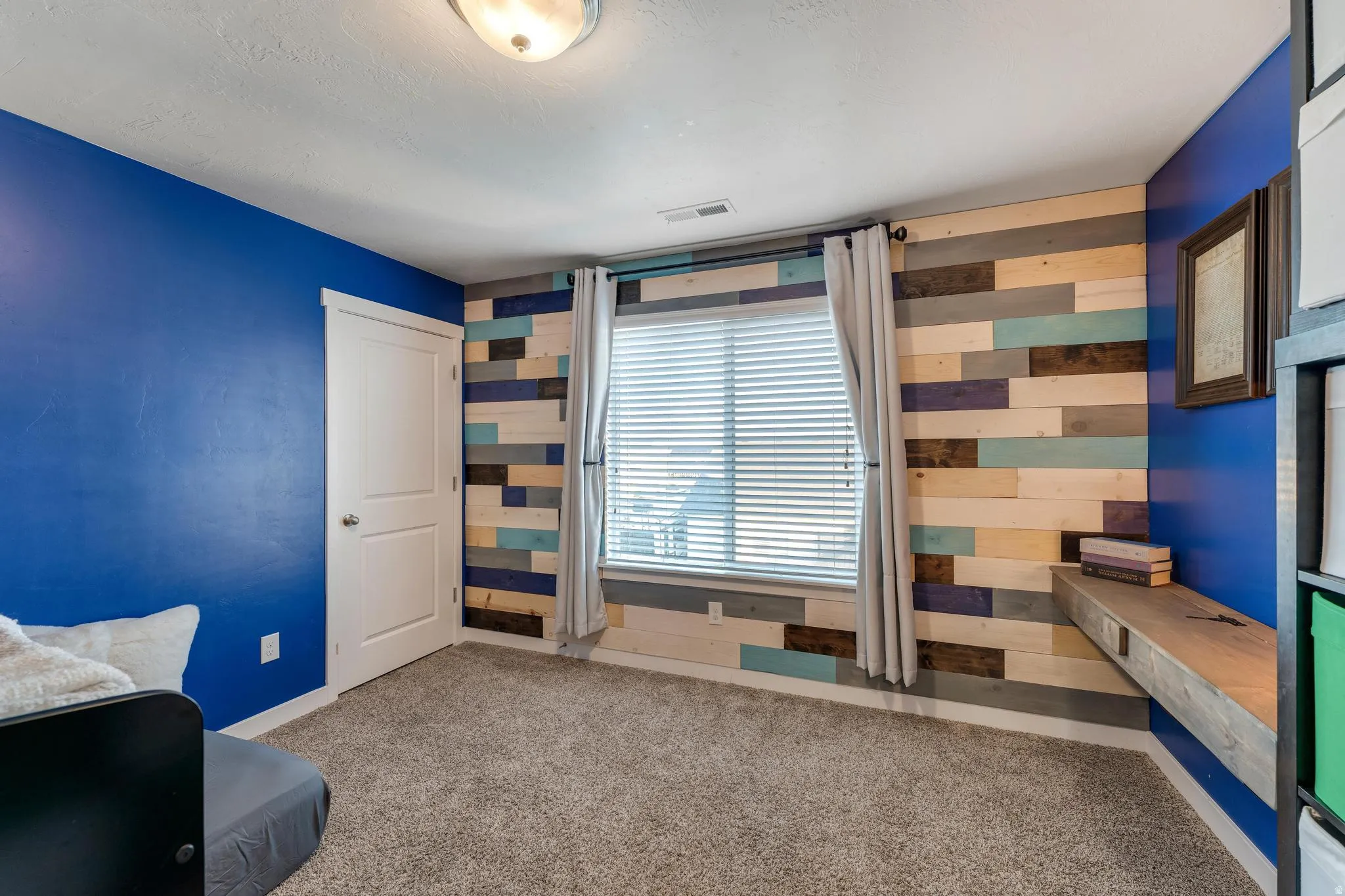 Interior room featuring a multi-toned wood plank accent wall with a built-in floating desk