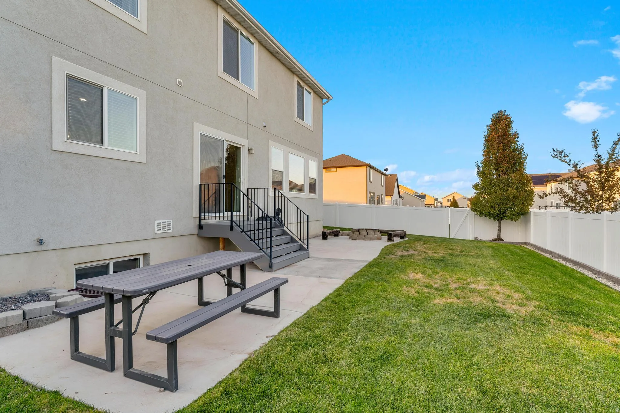 Expansive rear yard featuring a concrete patio, a privacy fence, and a manicured lawn