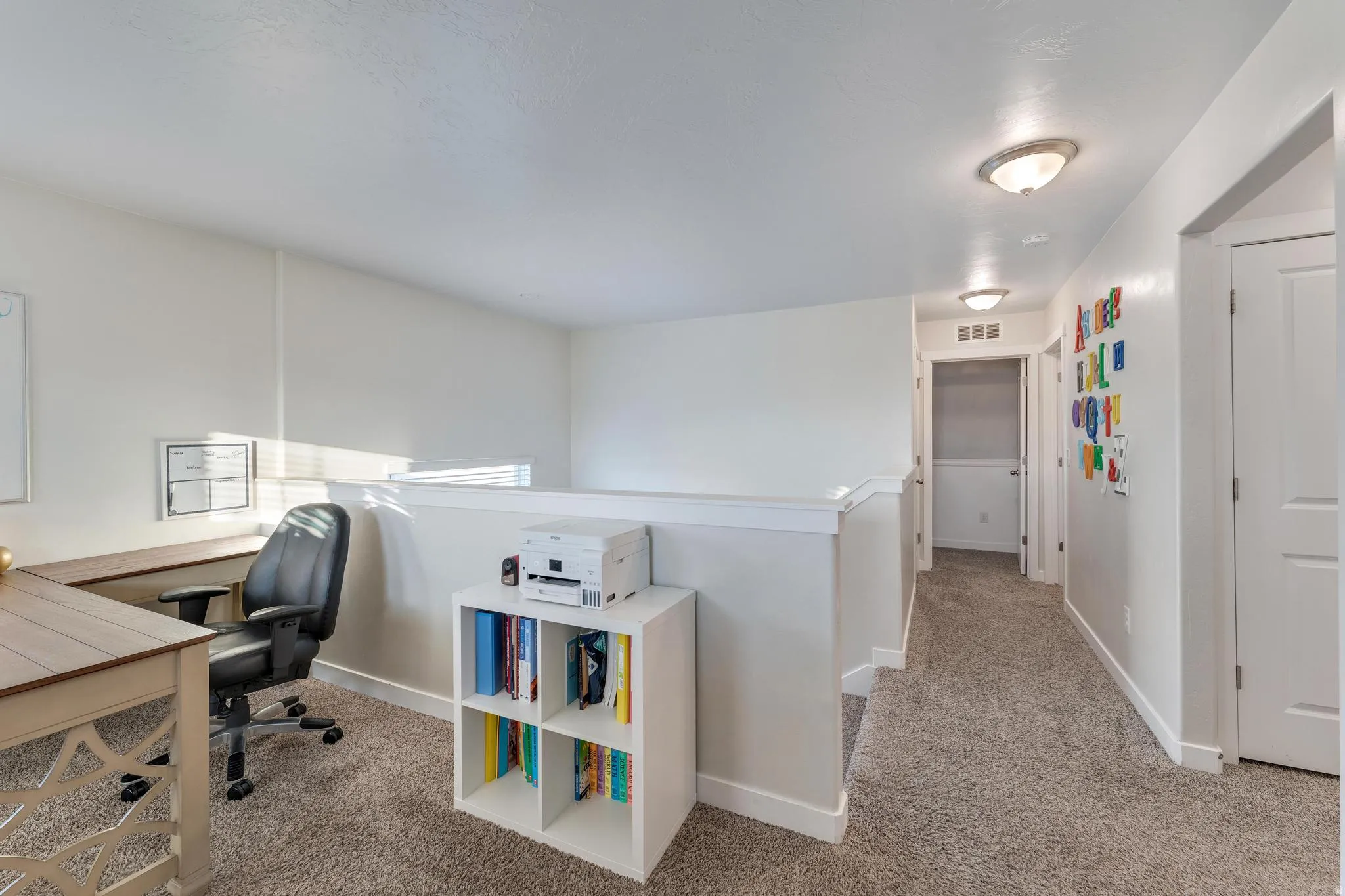 Upper-level landing featuring a built-in desk, plush carpet flooring, and recessed lighting