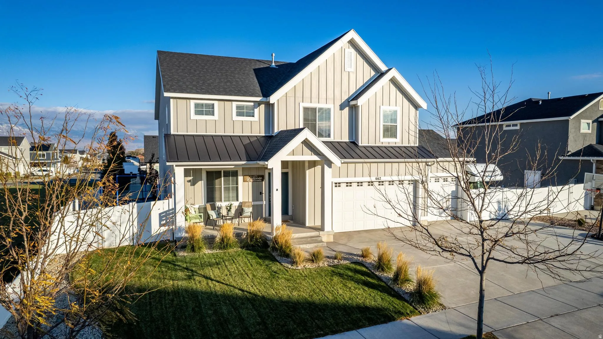 Contemporary two-story residence featuring light-toned vertical siding, a dark pitched roof, and a prominent front porch