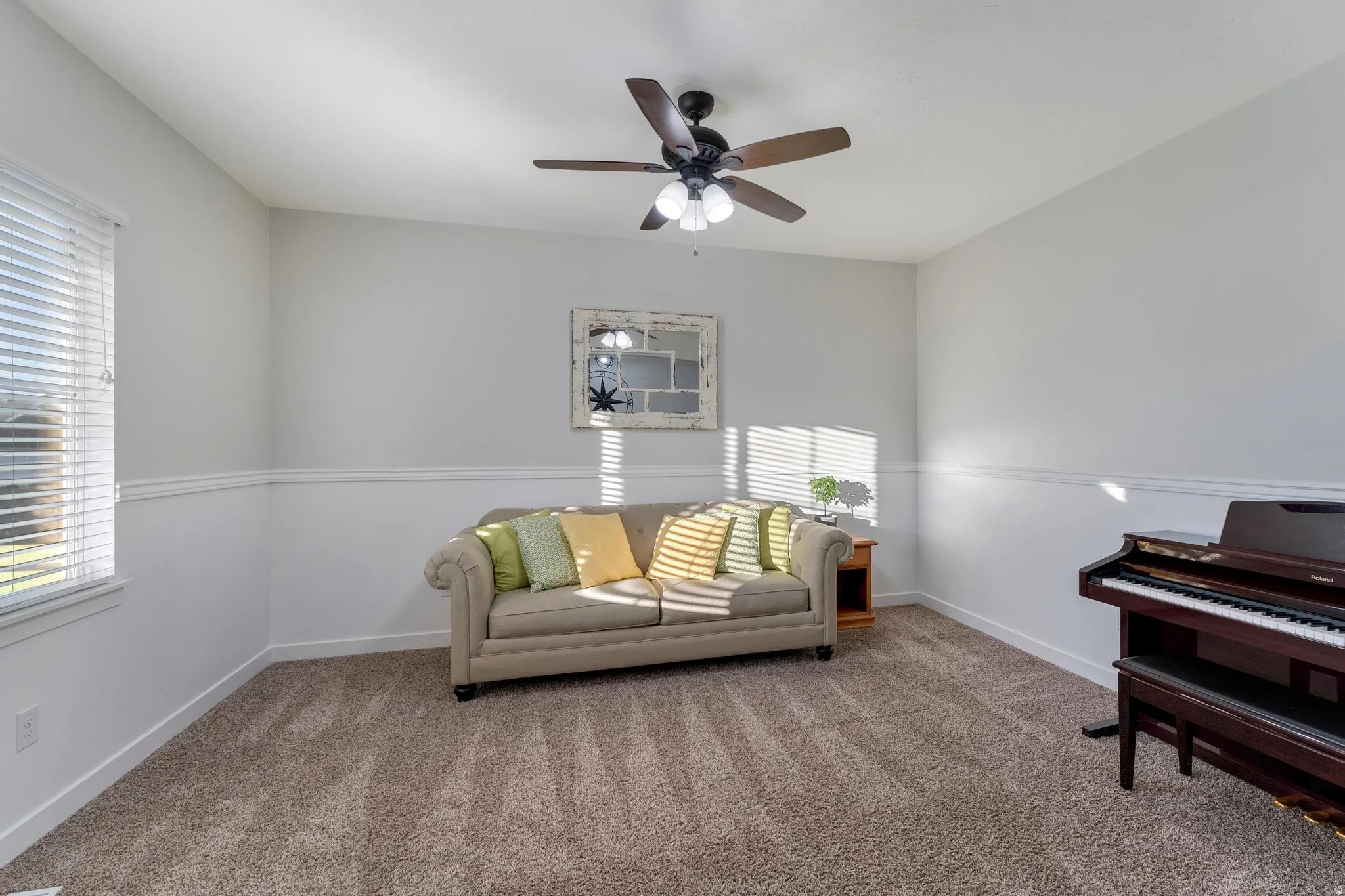 Spacious room featuring neutral paint, chair rail molding, a ceiling fan with light fixture, and plush carpet flooring