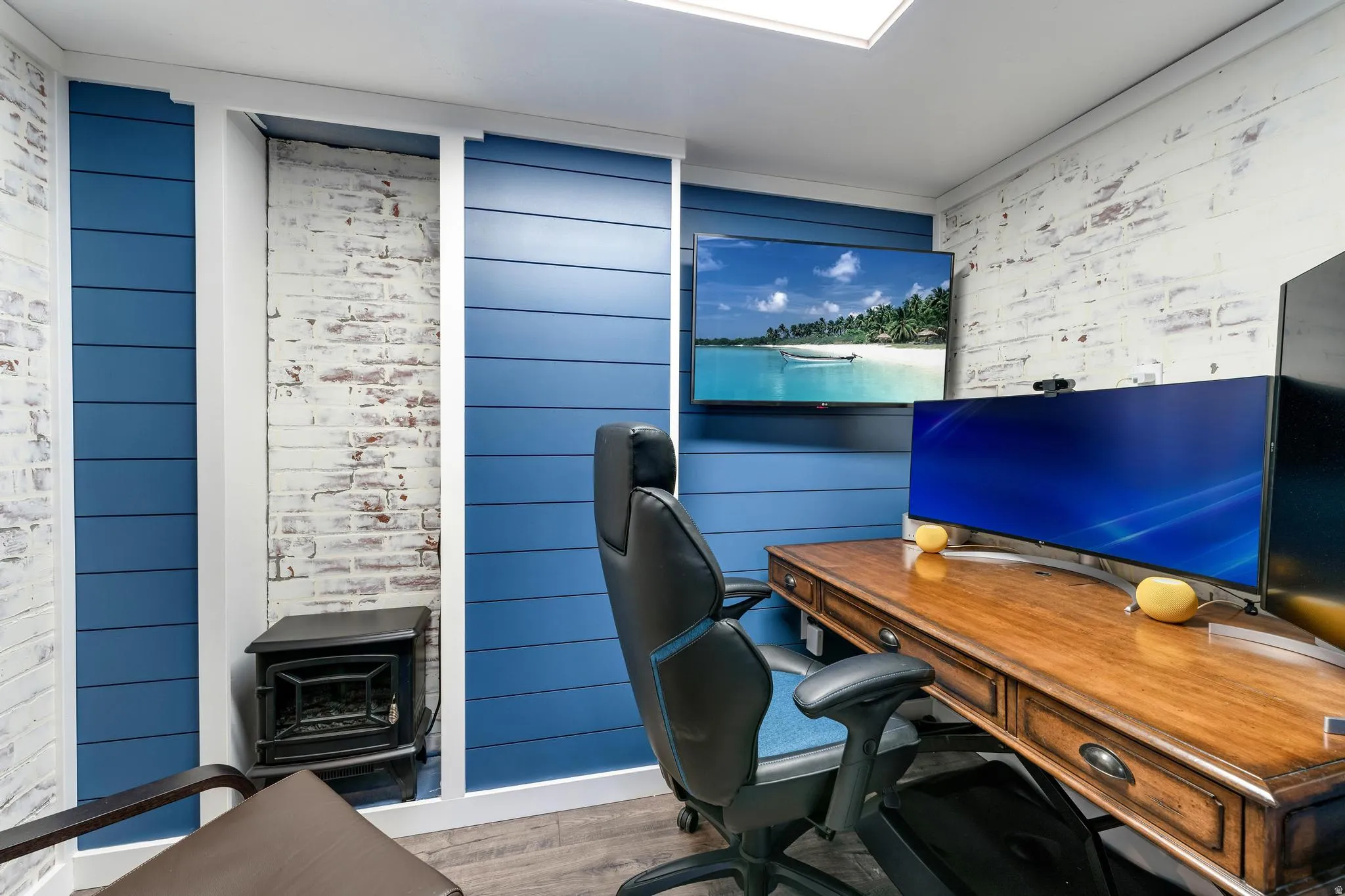 Dedicated workspace featuring blue shiplap paneling and distressed brick accent walls