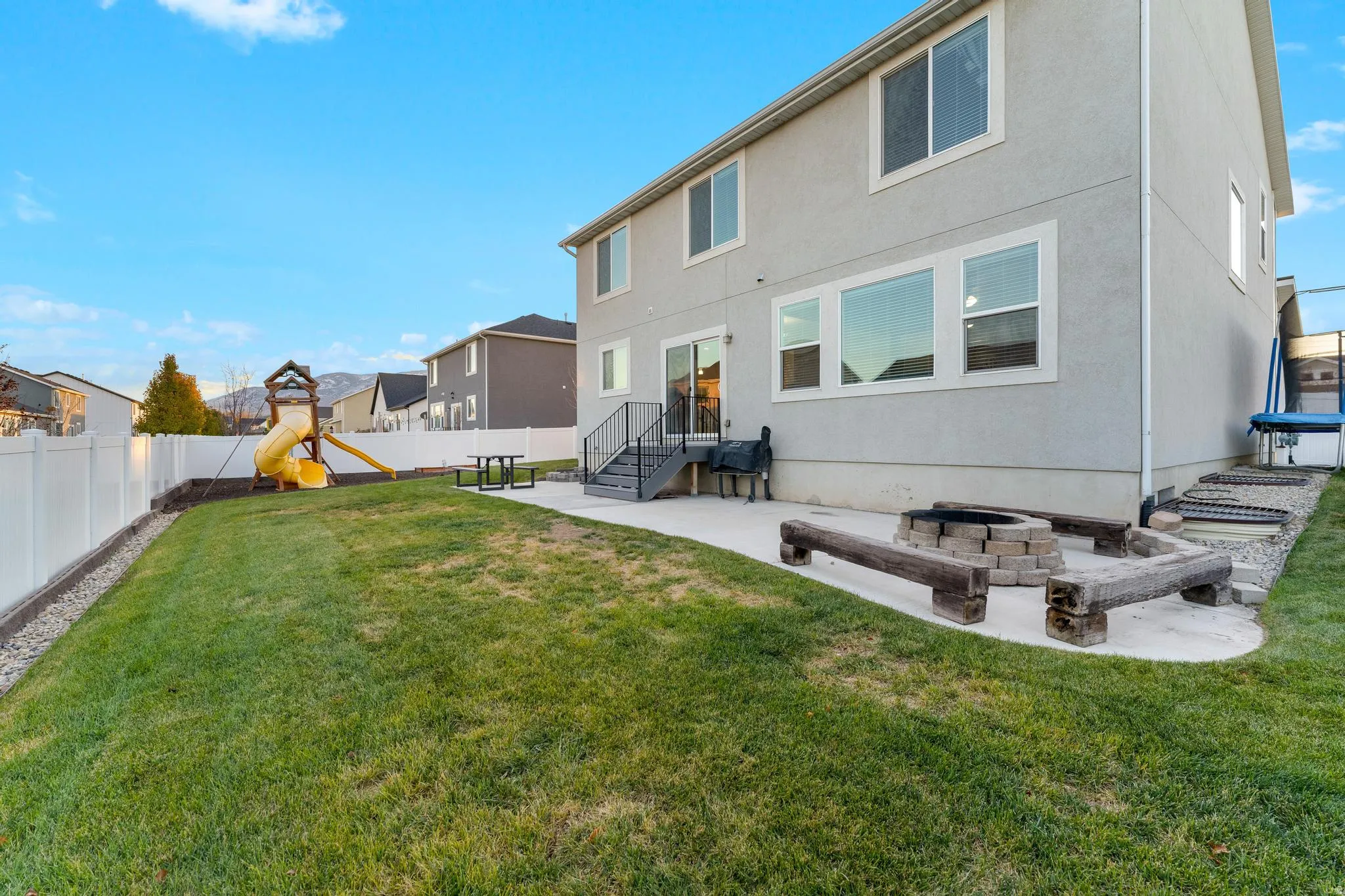 Expansive backyard featuring a lush lawn and perimeter white vinyl fencing