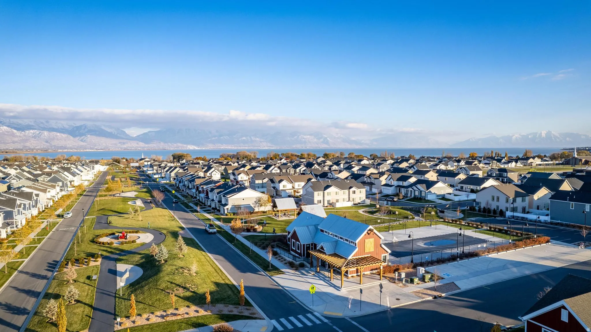 Aerial perspective showcasing a residential community with numerous homes, a prominent lake, and distant mountains