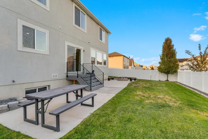 Expansive rear yard featuring a concrete patio, a privacy fence, and a manicured lawn