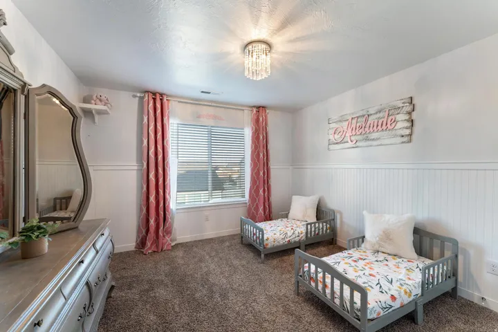 Bright room featuring a window with blinds, a crystal-style flush mount ceiling light, and white wainscoting