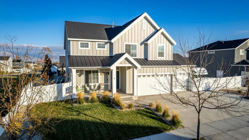 Contemporary two-story residence featuring light-toned vertical siding, a dark pitched roof, and a prominent front porch
