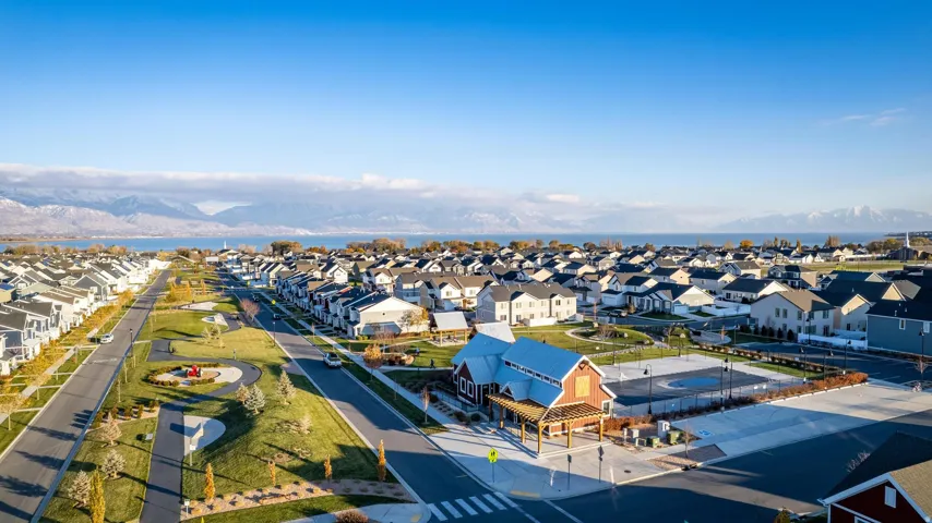 Aerial perspective showcasing a residential community with numerous homes, a prominent lake, and distant mountains