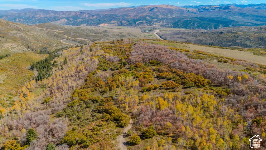 Expansive terrain featuring varied vegetation, mountainous topography, and distant roadways