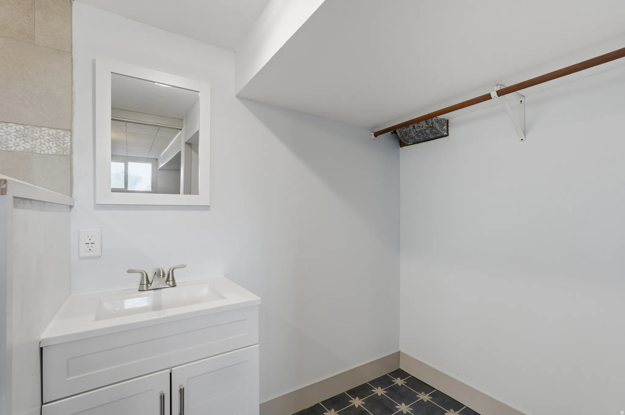 White vanity with integrated sink, brushed nickel faucet, and framed mirror