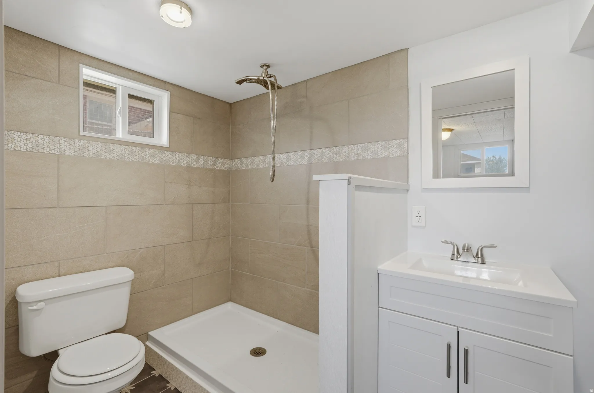 Shower with beige large format tile surround, decorative mosaic accent tile, and a rainfall showerhead