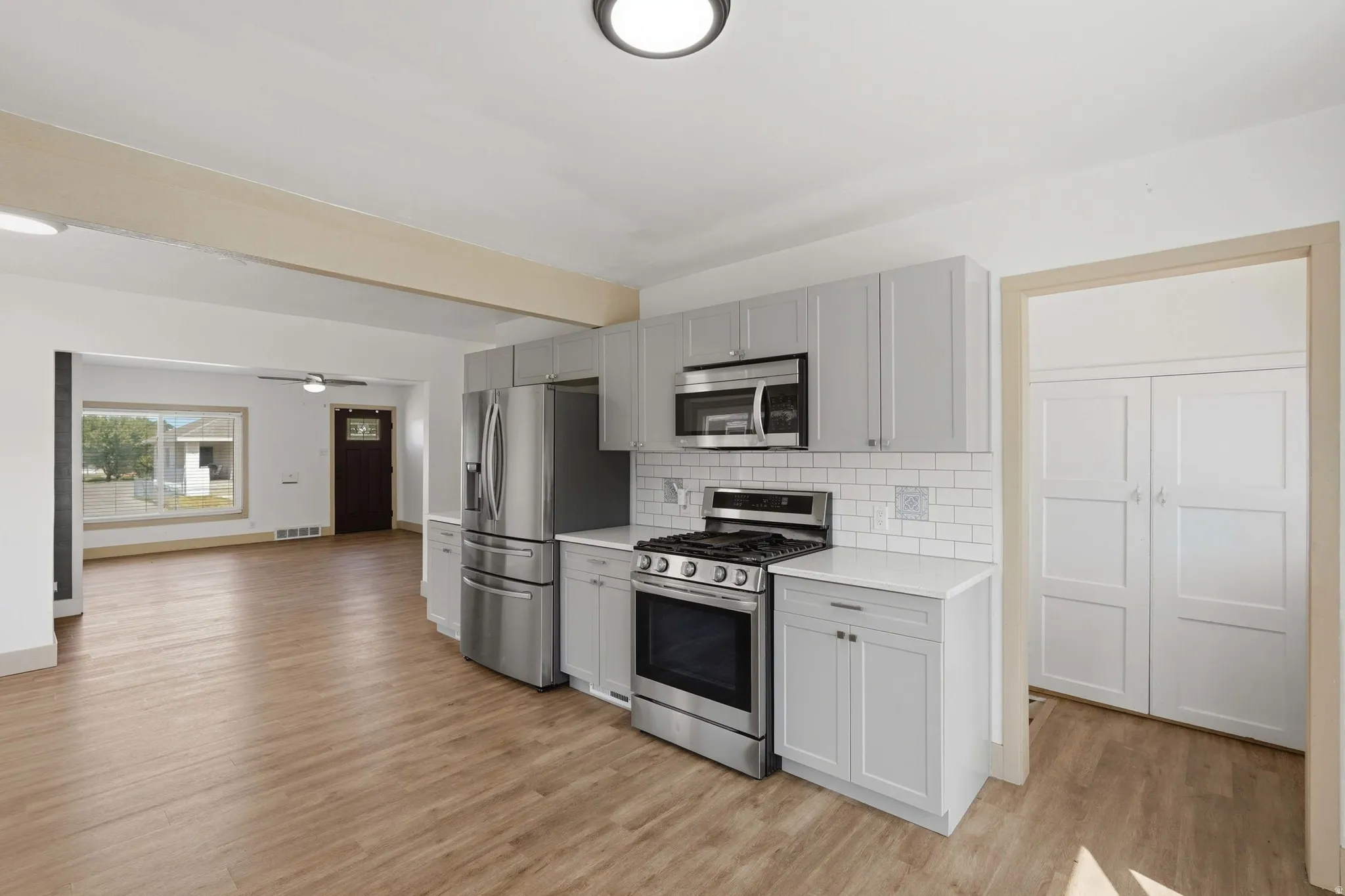 Kitchen featuring stainless steel appliances, light gray cabinetry, white subway tile backsplash, and light wood-finish flooring