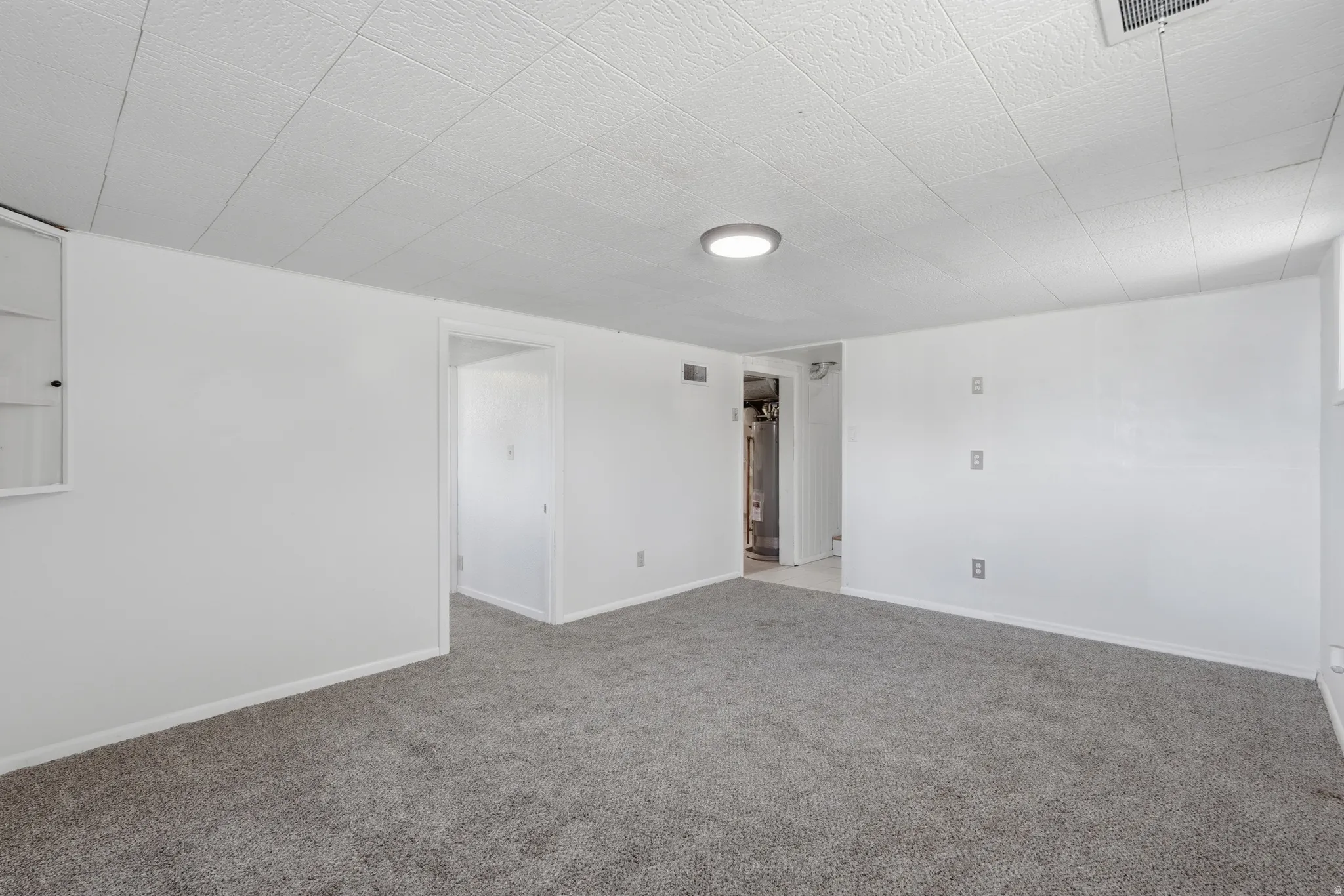 Carpeted interior space with white painted walls, white trim, and a drop ceiling