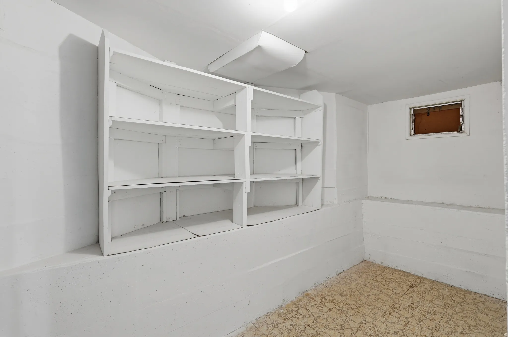Room featuring built-in shelving, painted white walls, and a window