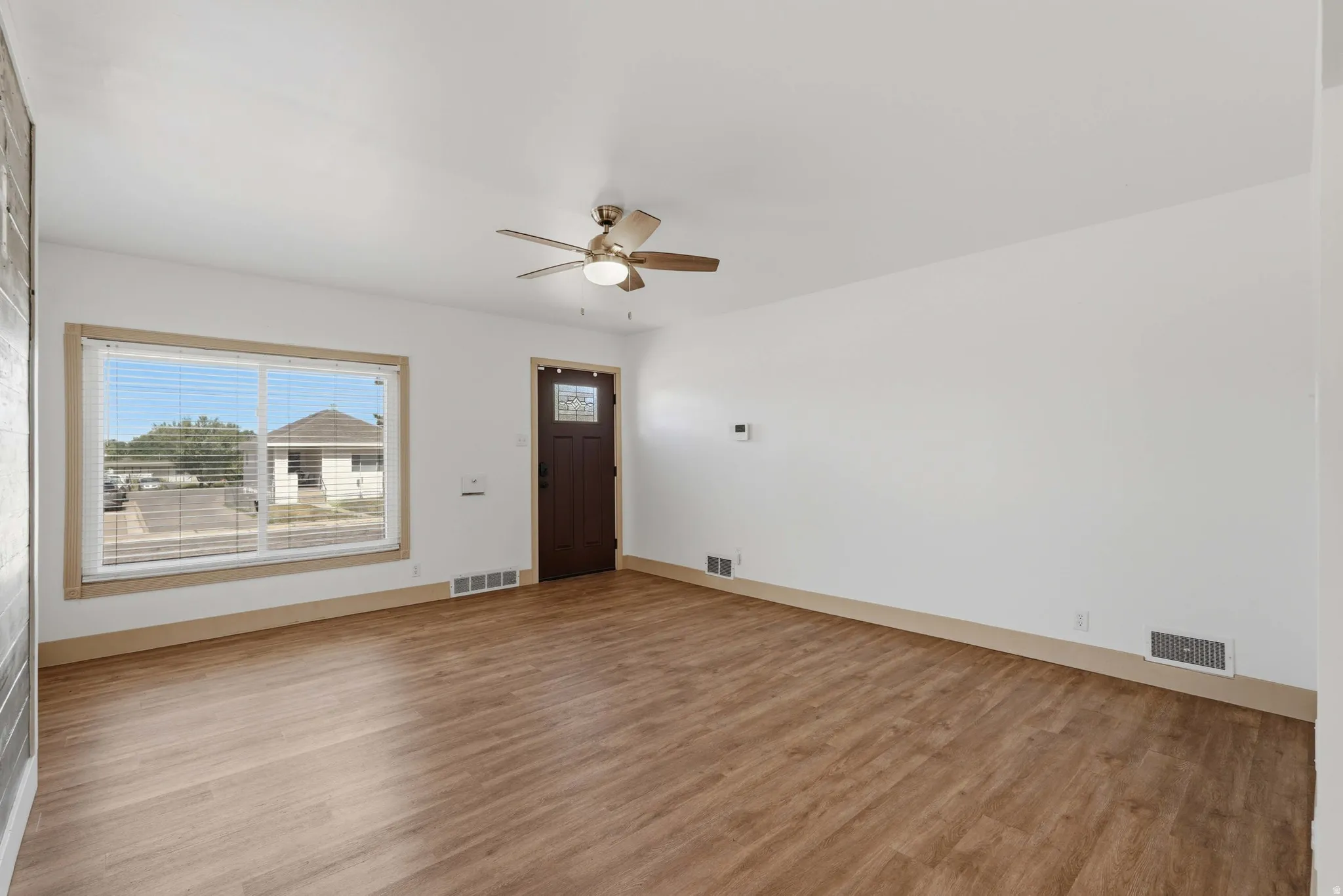 Spacious interior with wood-finish flooring, white walls, and a ceiling fan