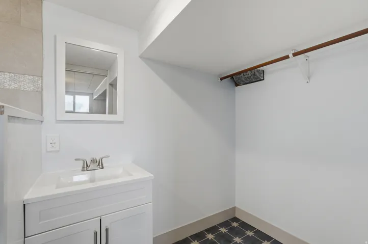 White vanity with integrated sink, brushed nickel faucet, and framed mirror